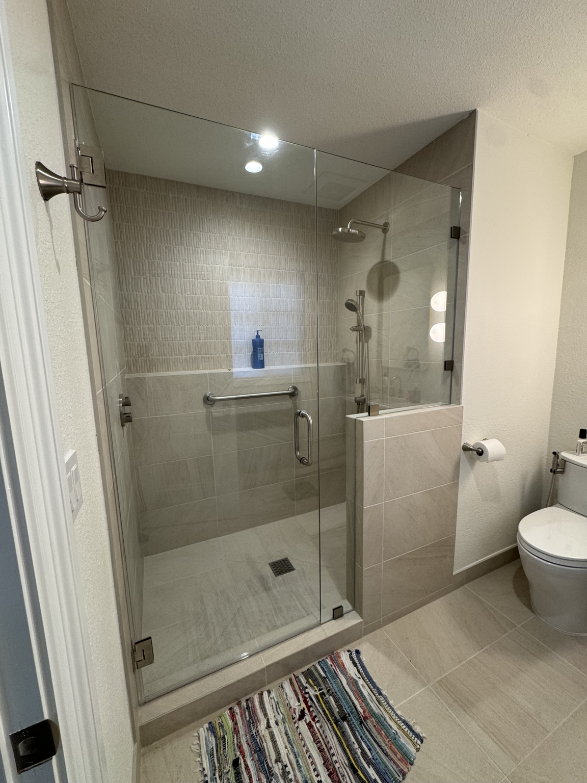 Frameless shower with brushed metal hardware