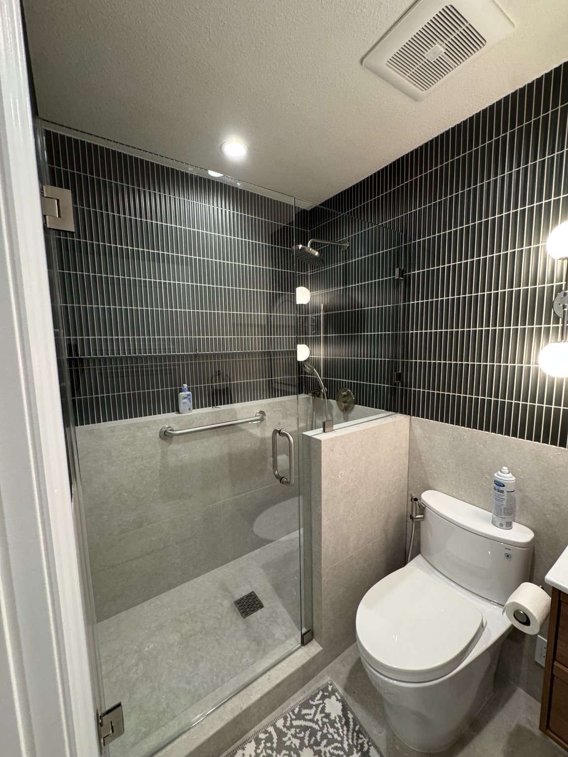 Glass shower in dark tiled bathroom